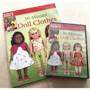 May include: A Sewing with Nancy 30-Minute Doll Clothes instructional book and a matching DVD case. Both items feature the title text and images of dolls wearing various handmade outfits, including cherry-print dresses and floral patterned pants.