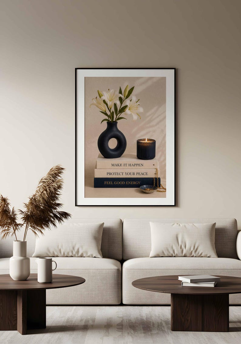 May include: A framed wall art print featuring a black donut-shaped vase with white lily flowers, a dark ribbed candle, and a stack of three books labeled MAKE IT HAPPEN, PROTECT YOUR PEACE, and FEEL GOOD ENERGY, with a small bowl and gold chain.