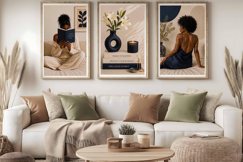 May include: A triptych of framed wall art prints displayed above a white sofa with beige and sage green pillows. The left print shows a person reading, the center print features white lilies in a black vase and books, and the right print shows a person.