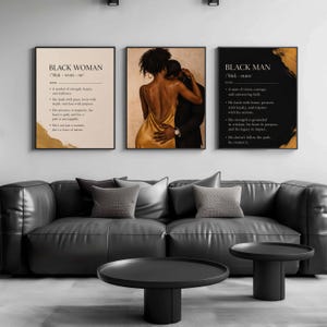 May include: Three framed wall art prints displayed above a black leather sofa. The left print defines Black Woman with gold accents. The center print shows a couple embracing. The right print defines Black Man with gold brushstroke details.