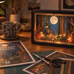 May include: A rectangular shadow box light featuring a layered paper forest scene with a wizard and a person foraging for mushrooms under a full moon. The frame is black with moon phase symbols. An assembly guide titled Moonlight Foragers is visible.