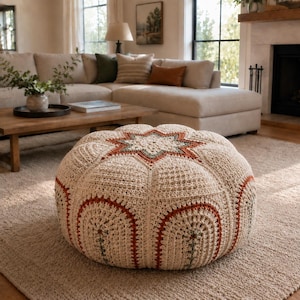 Può includere: Un pouf rotondo all'uncinetto color crema con un motivo a stella centrale e disegni ad arco in arancione ruggine e verde salvia. Il cuscino da pavimento testurizzato e fatto a mano presenta una densa lavorazione a maglia con motivo.