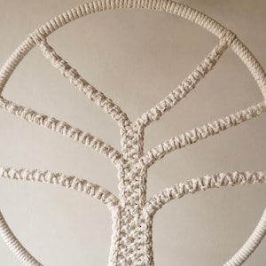 Pu&ograve; includere: Una decorazione da parete circolare realizzata in corda di cotone color bianco sporco con un design ad albero in macram&egrave;. La cornice esterna &egrave; un cerchio spesso di corda avvolta, con un tronco centrale e rami simmetrici annodati a mano.