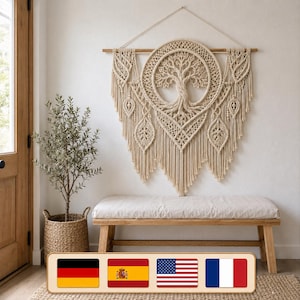 May include: A large off-white macrame wall hanging featuring a central circular tree of life design, intricate knotting patterns, and dangling leaf-shaped accents suspended from a horizontal wooden rod with a hanging cord.
