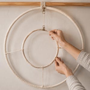 Pu&ograve; includere: Una decorazione da parete composta da due anelli in macram&egrave; color bianco sporco concentrici, sospesi a un bastone di legno orizzontale. L'anello esterno pi&ugrave; grande e quello interno pi&ugrave; piccolo sono collegati da cordini e clip metalliche.