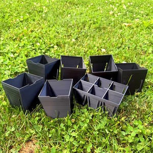 May include: A collection of dark gray, square-shaped plastic plant pots, including several individual containers and one multi-cell tray with six compartments, all featuring vertical side slits and open tops for gardening and seedling propagation.