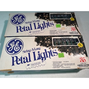 May include: Two rectangular cardboard boxes containing GE String-A-Long Petal Lights. Each box features a 35-light set with clear bulbs for indoor or outdoor use, displaying the GE logo, product name, and a graphic of lights on a pine branch.