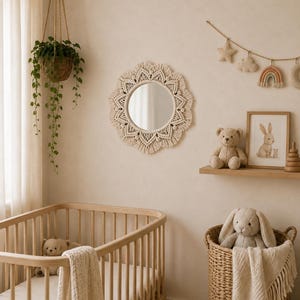 Puede incluir: Un espejo de pared redondo enmarcado con un intrincado cordón de macramé en color blanco roto con un patrón de rayos de sol. El espejo cuenta con un cristal circular central rodeado de diseños de fibras anudadas con textura decorativa.