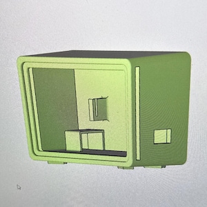 May include: A digital 3D model of a light green rectangular box-shaped enclosure displayed on a computer screen within the SOLIDWORKS xDesign software interface. The model features a hollow interior, a front frame, and a small rectangular cutout.