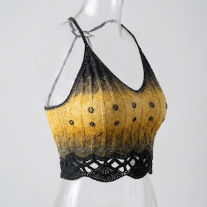 May include: A sleeveless crochet crop top featuring a gradient color transition from black at the top and bottom to a golden yellow center. The garment has a V-neckline, thin straps, and a scalloped hem with small black bead embellishments.