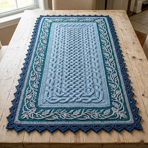 May include: A rectangular crochet table runner featuring a central light blue panel with an intricate cable-knit style braided pattern. It is bordered by a teal frame with a light gray leaf vine motif and a dark blue scalloped crochet edge.