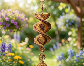 Può includere: Un ornamento sospeso all'uncinetto a forma di spirale con bande alternate di filato marrone e giallo senape. L'oggetto è sospeso da una catena color oro fissata a un anello di legno e rifinito con un gruppo di perline e un fiore all'uncinetto.
