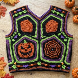 May include: A sleeveless crochet vest featuring a patchwork of black, orange, and lime green hexagonal motifs. The design includes detailed appliques of jack-o'-lanterns, spider webs, ghosts, bats, and small pumpkin beads throughout the garment.