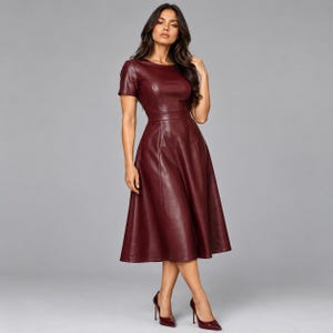 Könnte beinhalten: Ein dunkelburgunderfarbenes Midikleid aus einem glatten, lederartigen Material. Das Kleid verfügt über kurze Ärmel, einen Rundhalsausschnitt, ein eng anliegendes Oberteil und einen ausgestellten Rock, der unterhalb der Knie endet.