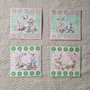 Op de afbeelding: Vier vierkante spaarchallenge-kaarten met bloemen- en vogelillustraties en theeserviezen. Twee kaarten hebben een lichtgroene achtergrond met roze cirkels gelabeld 1 of 2, en twee hebben een lichtroze achtergrond met groene cirkels gelabeld 1 of 2.