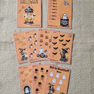 Op de afbeelding: Een verzameling rechthoekige Halloween-spaaruitdagingskaarten met oranje achtergronden. De kaarten bevatten illustraties van geesten, pompoenen, vleermuizen, katten en heksen, samen met tekst waaronder Happy Halloween, Ghostlist en Roll to Ghoststuff.