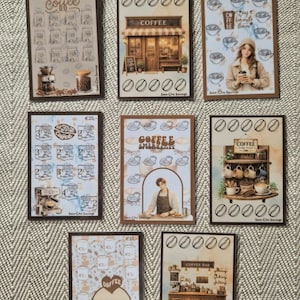 Op de afbeelding: Acht rechthoekige papieren spaartrackers met illustraties in koffiethema, waaronder koffietentjes, espressomachines en mokken. Elke kaart toont verschillende geldbedragen, koffieboonpictogrammen en de tekst Sma-Cha Savings.