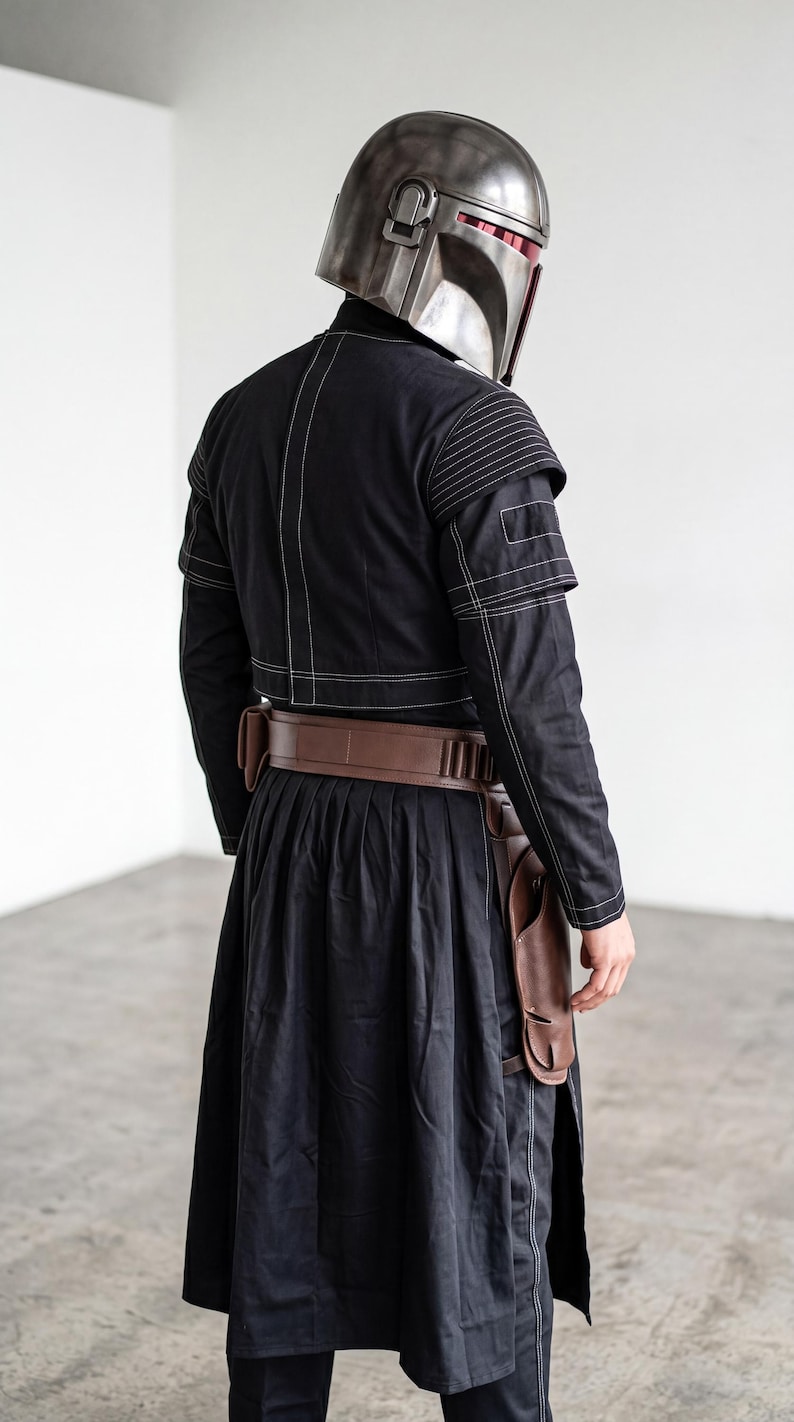 Op de afbeelding: Een metallic zilveren helm met een donker vizier gecombineerd met een zwart jasje met witte contraststiksels op de schouders en rug. Een bruine lederen utility-riem met holster wordt gedragen over een lange zwarte rok met zijsplit.