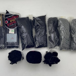Peut inclure: Assortiment de fils à tapis noirs et gris dans des sacs en plastique individuels. Le fil est étiqueté "Rug Yarn", "Bulky Rug Yarn" et "Target".