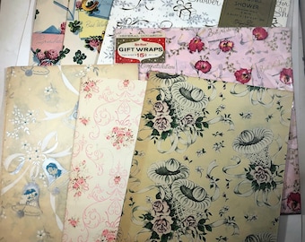 May include: A stack of vintage wrapping paper with floral and wedding shower designs. The paper features various colours, including pink, green, yellow, and blue. The text on the paper includes "Best Wishes", "Congratulations", "For Your Shower", and "Wedding Shower".