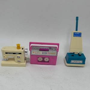 May include: Three vintage toy appliances in white, pink and blue. A white sewing machine with the word "GALOOB" printed on it, a pink cassette player with two buttons, and a blue and white vacuum cleaner with the word "GALOOB" printed on it.