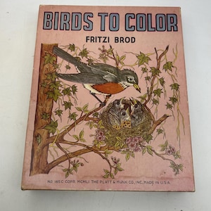 May include: A vintage colouring book cover featuring a colourful illustration of a robin bird with its young in a nest. The title of the book is "Birds to Colour" by Fritzi Brod. The book cover is pink with a brown tree branch and green leaves.