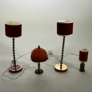 Puede incluir: Colección de lámparas en miniatura con pantallas de terciopelo rojo y bases de latón. Las lámparas incluyen dos lámparas de pie altas, una pequeña lámpara de mesa y una lámpara en miniatura, todas con cables eléctricos.