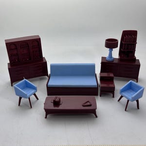 May include: A miniature dollhouse furniture set featuring a dark maroon hutch, a light blue sofa, two light blue armchairs, a dark maroon coffee table, a dark maroon side table, a dark maroon bookshelf, and a light blue table lamp.