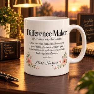 Könnte beinhalten: Ein weißer Keramikbecher mit dem schwarzen Text Difference Maker, einer phonetischen Aussprache und einer Definition, die eine Lehrkraft beschreibt, die kleine Momente in Lebenslektionen verwandelt. Das Design enthält florale Akzente und den Namen Mrs. Harper.