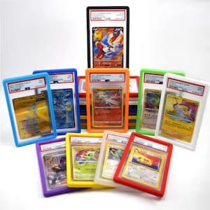 May include: A collection of ten graded trading cards encased in colourful plastic slabs. The cards feature various illustrated characters and text, including Cinderace V, Reshiram, and Raikou. The slabs are arranged in a tiered display with red, orange, yellow, green, blue, and purple borders.