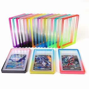 May include: A collection of rectangular, transparent plastic card holders in various neon colors, including pink, purple, yellow, blue, green, and orange. Three holders contain illustrated trading cards, while others are empty and stacked upright.