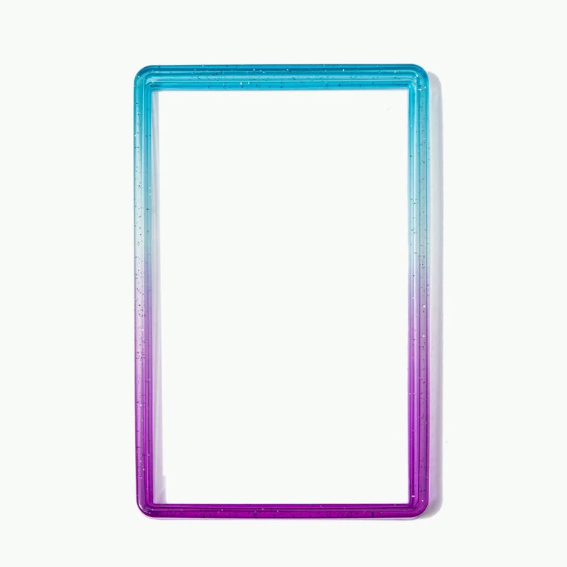 May include: A rectangular frame with a smooth, glossy finish featuring a vertical gradient color transition from bright blue at the top to deep purple at the bottom. The material is translucent and contains small, embedded glitter particles.