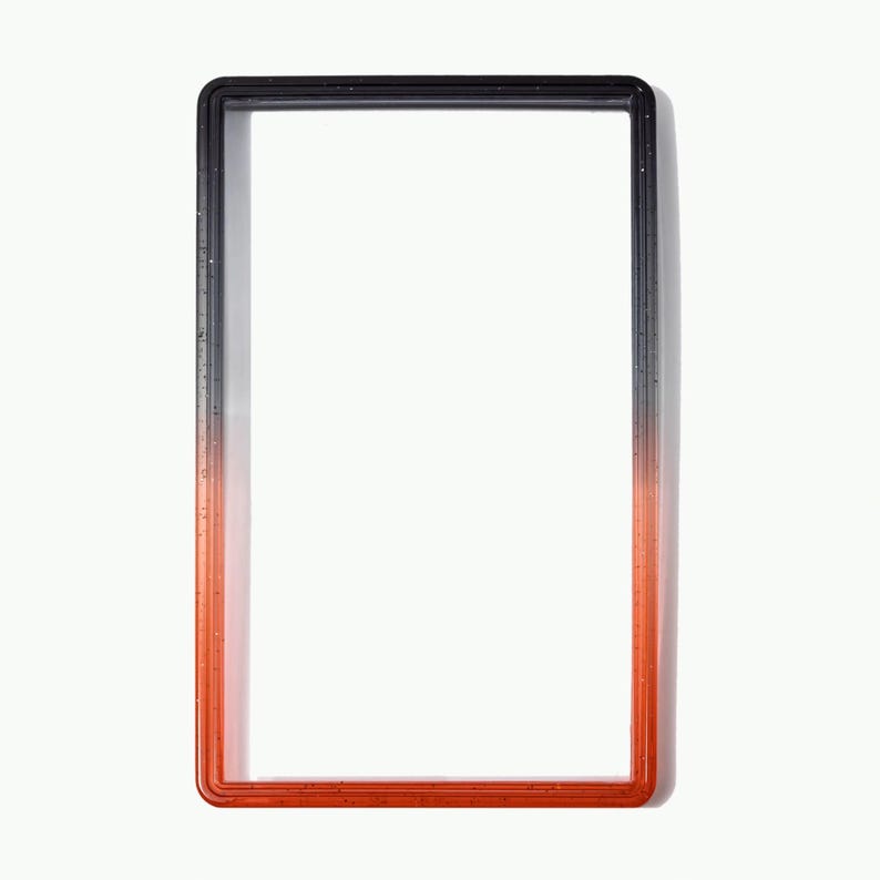 May include: A rectangular frame featuring a smooth gradient transition from black at the top to a vibrant orange at the bottom. The frame has a glossy finish with subtle embedded glitter particles throughout the material, creating a reflective surface.