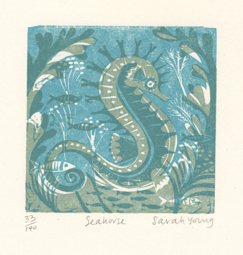 May include: A blue and green linocut print of a seahorse surrounded by seaweed and fish. The print is numbered 33/140 and signed "Seahorse" and "Sarah Young".