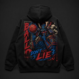 May include: A black hooded sweatshirt featuring a graphic print of a samurai in blue and red armour holding a basketball on one finger. The text "BALL DON'T LIE" is printed in red and blue, accompanied by Japanese characters and a pagoda silhouette.