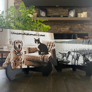 K&ouml;nnte beinhalten: Zwei rechteckige Plaketten auf schwarzen St&auml;ndern. Die linke Plakette zeigt einen Golden Retriever und eine schwarz-wei&szlig;e Katze mit dem Text Unconditional Love. Die rechte Plakette ist ein Schwarz-Wei&szlig;-Bild von drei Hunden an einem See.
