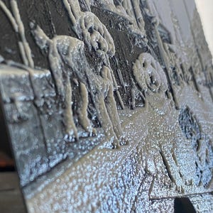 K&ouml;nnte beinhalten: Eine 3D-gedruckte Platte mit einem erhabenen, texturierten Relief eines Hundes, der auf einer gepflasterten Fl&auml;che steht. Das Objekt ist einfarbig, aus einem hellgrauen Material mit matter Oberfl&auml;che gefertigt und zeigt detaillierte Konturen.
