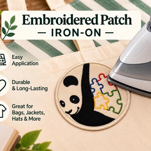 May include: A circular iron-on embroidered patch featuring a black and white panda bear design with colorful puzzle pieces on a beige canvas tote bag. An iron is positioned over the patch, with text reading Embroidered Patch IRON-ON.