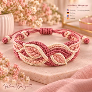 Pode incluir: Uma pulseira de macramé com um padrão de folhas trançadas em tons de rosa antigo, rosa claro e creme. A pulseira possui um fecho deslizante ajustável com pequenas extremidades com nós. O texto na imagem diz Available in 4 Languages.