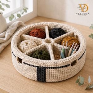May include: A round, beige crocheted yarn organizer basket with six internal compartments. It contains balls of yarn in rust, black, cream, olive green, and mustard yellow, along with several metal crochet hooks and small circular stitch markers.