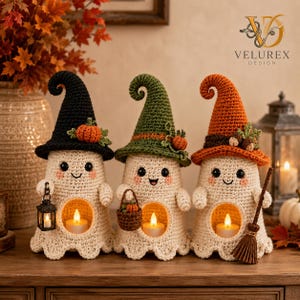 May include: Three crocheted ghost figurines with hollow centers containing tea lights. The ghosts wear pointed hats in black, green, and orange, decorated with small pumpkins or acorns. One holds a lantern, one a basket, and one a broom.