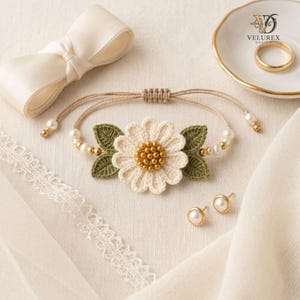 Puede incluir: Una pulsera con una margarita central de ganchillo blanco con centro de cuentas doradas, flanqueada por dos hojas de ganchillo verde. La banda es de cordón fino con pequeñas perlas blancas y cuentas doradas, junto a dos pendientes de perla.