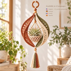 May include: A hanging crochet plant holder featuring a central basket holding an air plant, surrounded by two curved panels in rust orange and olive green. It includes a wooden ring at the top, wooden beads, and a multi-coloured tassel at the bottom.