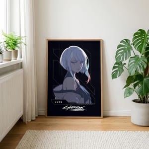 May include: A framed rectangular wall art print featuring an anime-style character with short white hair and blue highlights. The character is labeled LUCY, and the print includes the Cyberpunk Edgerunners logo in white text on a black background.