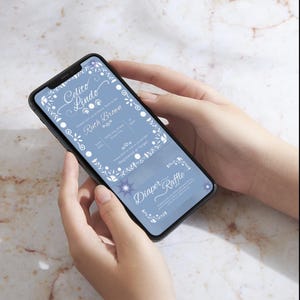 Peut inclure: Un smartphone affichant une invitation numérique pour une fête prénatale et une carte de tombola à couches sur un fond bleu clair avec des bordures florales blanches et du texte cursif indiquant Celito Lindo, Ruth Brown et Diaper Raffle.