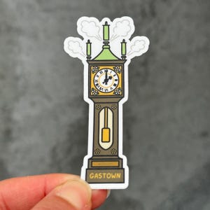 Könnte beinhalten: Ein Aufkleber mit einer Cartoon-Illustration einer Standuhr. Das Zifferblatt ist gelb mit römischen Ziffern, die Zeiger zeigen auf 11 Uhr. Die Uhr ist braun mit grünen Akzenten und dem Wort "GASTOWN" am Sockel.