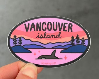 May include: Oval sticker with a pink and purple sunset design, featuring the text "Vancouver Island" and an orca whale. The sticker also includes trees, water, and stars. The artist's name, "@ashsgreen", is at the bottom.