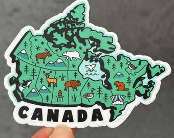 Puede incluir: Una pegatina con la forma de Canadá, con un mapa verde que incluye ilustraciones de fauna y monumentos. La palabra "CANADA" está impresa en blanco en la parte inferior. La pegatina está sujeta por una mano.