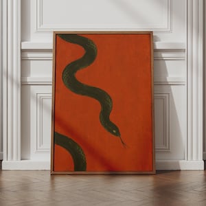 May include: A rectangular wall art piece featuring a dark green snake with a visible eye and tongue, depicted in a winding, S-shaped motion against a solid, vibrant burnt orange background, enclosed within a simple, thin wooden frame.