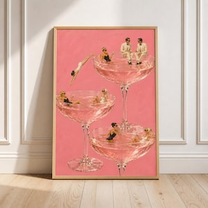 May include: A framed art print featuring a collage on a solid pink background. Three large stemmed cocktail glasses are filled with liquid, with small figures of people in swimwear and formal attire swimming or sitting inside the glasses.